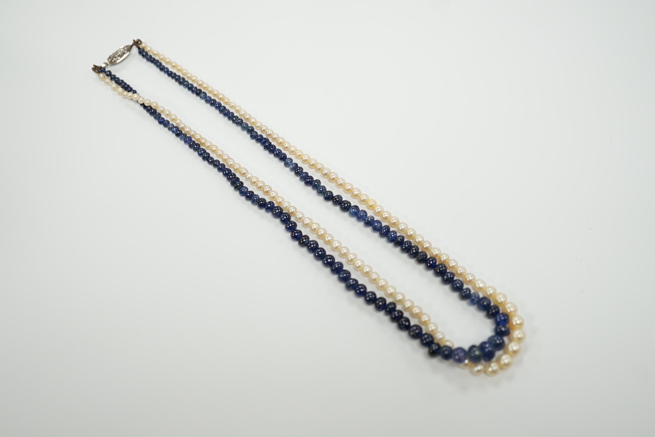 A twin strand gradated seed pearl and graduated sapphire bead necklace, with diamond chip set white metal clasp, 36cm, in original F. Chiappe, Gioielliere, Genova box.